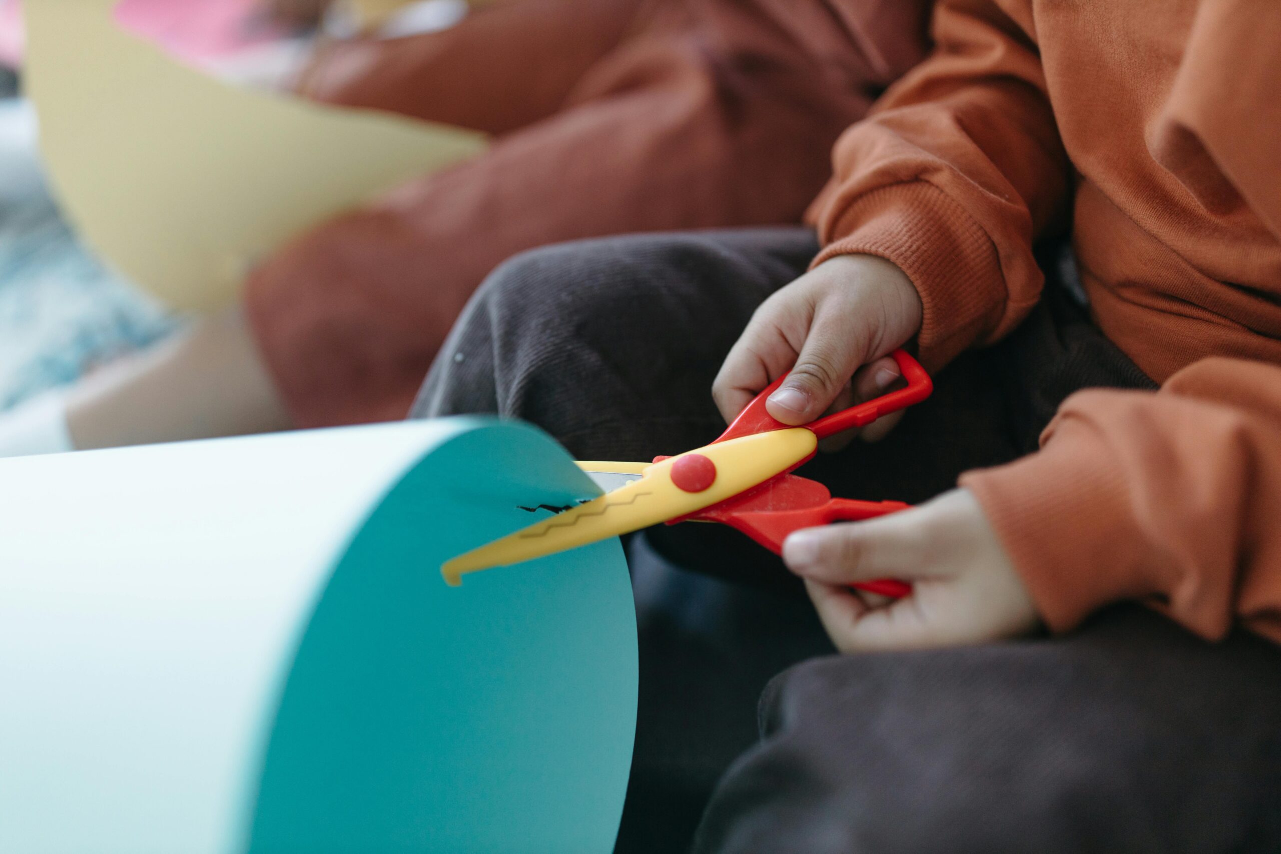 Close-up of children using colorful scissors to cut paper during a craft activity.